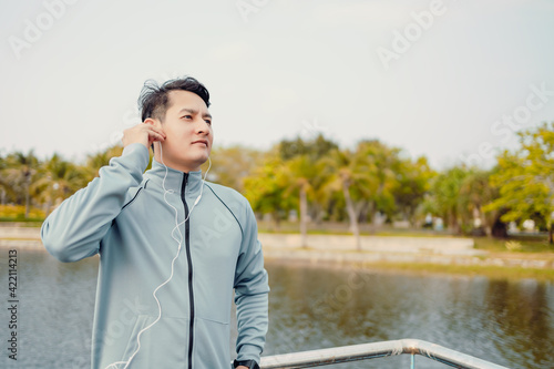 Young sportman jogging and listening music in the park.