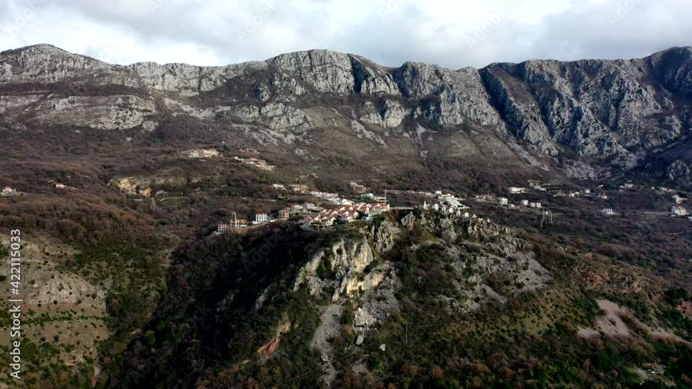 Small houses with orange roofs on high mountain range with brown bush and trees during autumn on sunset Small houses with orange roofs on high mountain range with brown bush and trees during autumn on sunset