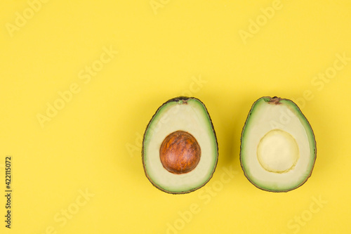 Avocado cut in half on bright yellow background