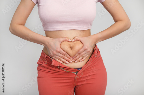 Love your body positive woman. Cropped studio shot of a woman holding her hands in a shape of heart on her fatty stomach. photo