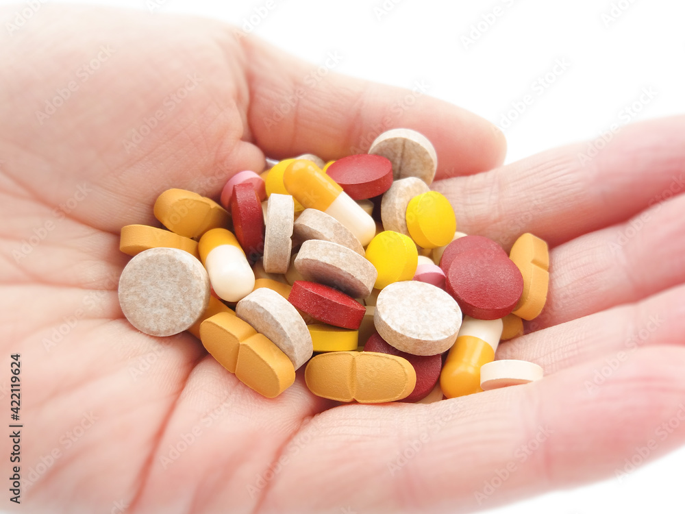 Multicolored pills in hand on white background. Concept of health Multicolored pills in hand on white background. Concept of health