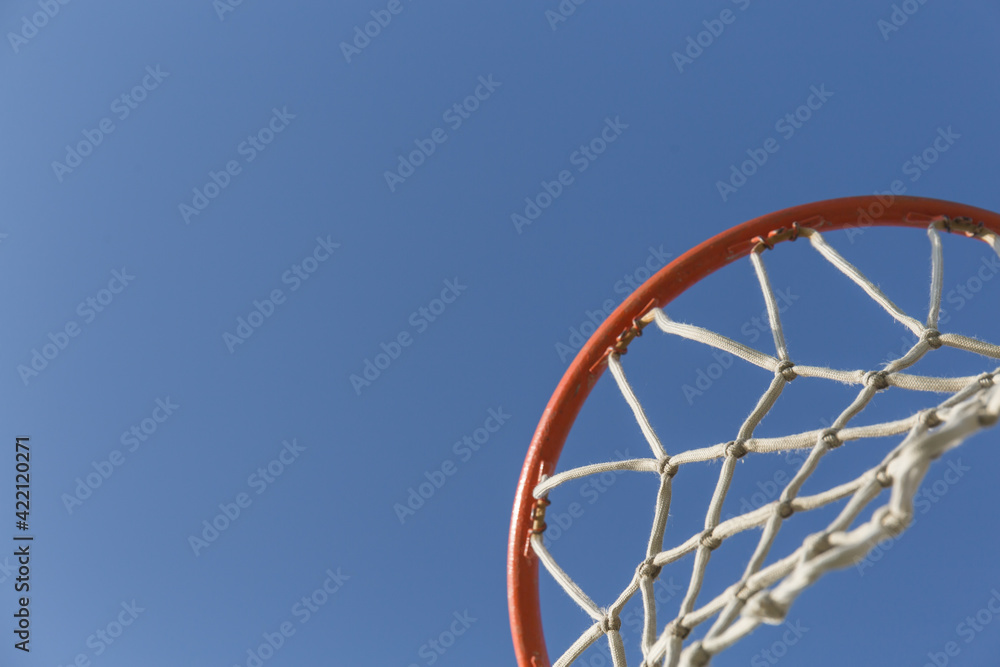 close-up of a basketball hoop seen from below, blue sky is visible in the background close-up of a basketball hoop seen from below, blue sky is visible in the background