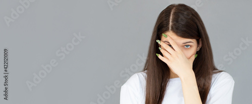Billede på lærred Young woman with hand on her face isolated on gray background, facepalm