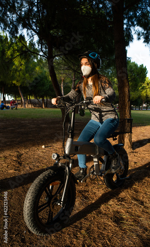 Girl with a mask on a bike ride in the park.