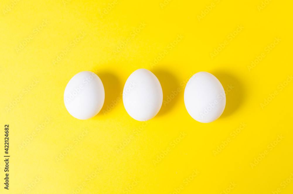 three chicken eggs lie on a yellow background three chicken eggs lie on a yellow background