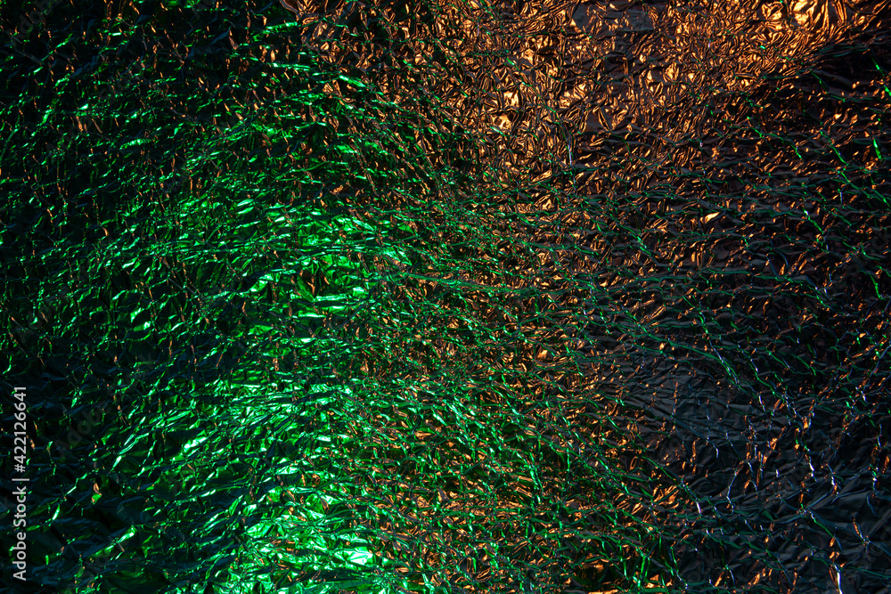 Obraz premium Abstract gold and green aluminum wrinkled foil background texture reflecting green and golden yellow light
