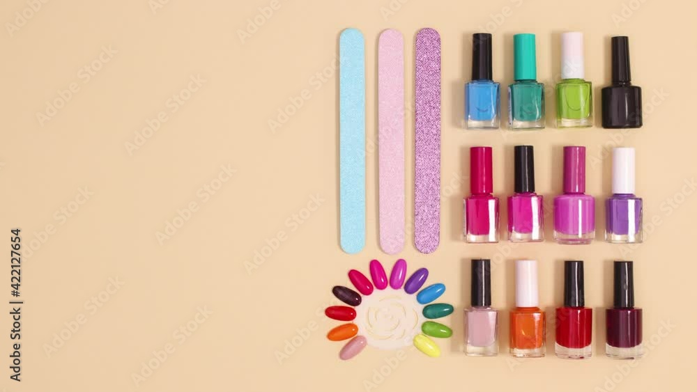 Vibrant nail polishes and manicure tools move on beige background. Stop motion Vibrant nail polishes and manicure tools move on beige background. Stop motion