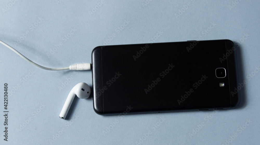 Fototapeta premium Mobile phone and wireless earpiece on white background