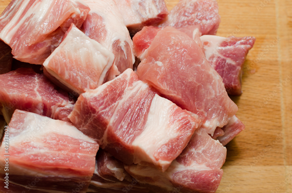 Raw pork, lying on a wooden board, cut into small cubes and ready to marinate. Close-up Raw pork, lying on a wooden board, cut into small cubes and ready to marinate. Close-up