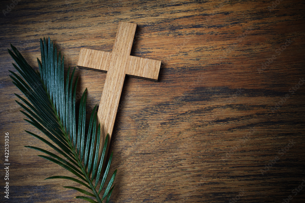 Palm sunday background. Cross and palm on wooden background.