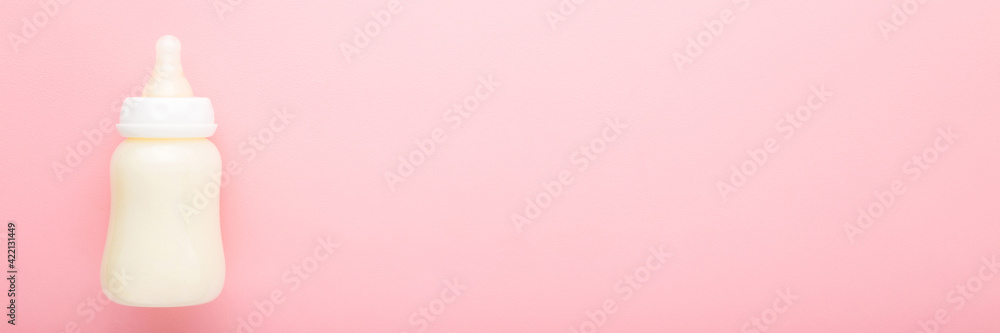 Bottle of white milk on light pink table background. Baby feeding concept. Pastel color. Closeup. Wide banner. Empty place for text. Top down view. Bottle of white milk on light pink table background. Baby feeding concept. Pastel color. Closeup. Wide banner. Empty place for text. Top down view.