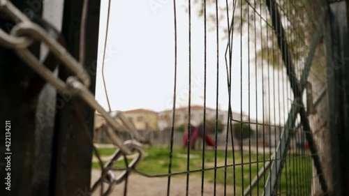 Close up on locked doors of entrance of playground, located at Kifissia, Athens, Greece, during coronavirus lockdown. Pan shot with shallow depth of field photo