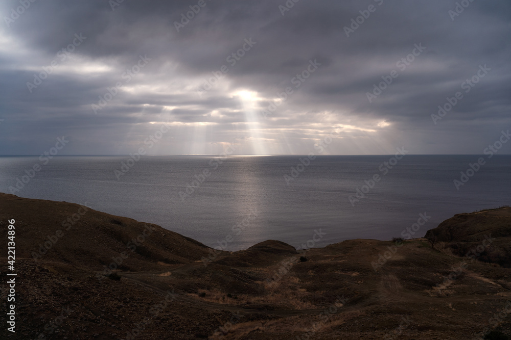 Sun rays make their way through dramatic clouds. Weather turns bad in the evening. Beautiful seascape