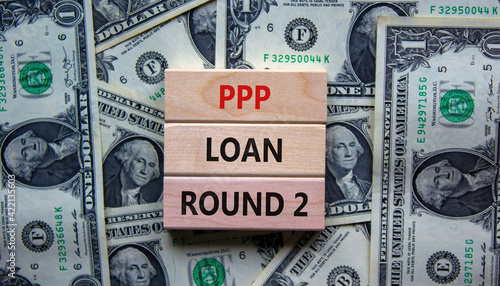 PPP, paycheck protection program loan round 2 symbol. Concept words PPP loan round 2 on blocks on background from dollar bills. Business, PPP - paycheck protection program loan round 2 concept.