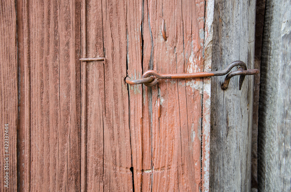 Old wooden door, brown, closed on a metal hook. Close-up. Vintage Old wooden door, brown, closed on a metal hook. Close-up. Vintage