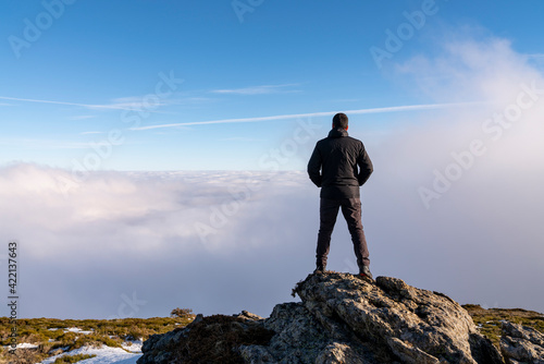 Hombre mirando sobre las nubes en la montaña