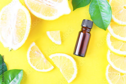Sliced lemon and essential oil on a yellow background. Use in adjunctive treatment. Citrus oil.