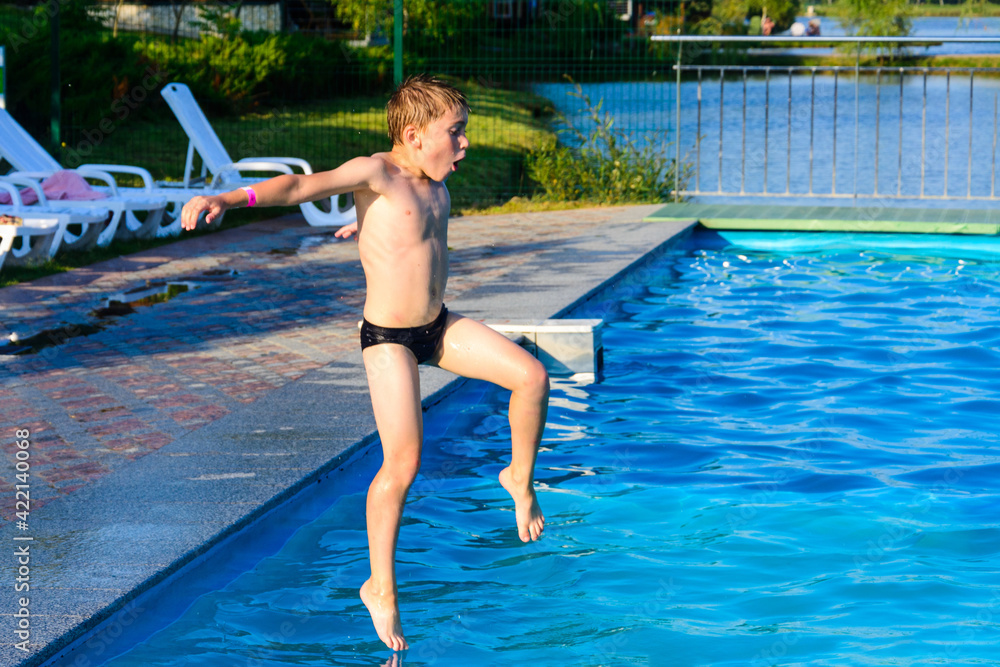 The boy jumps into the pool, children's games and entertainment in the aqua park.