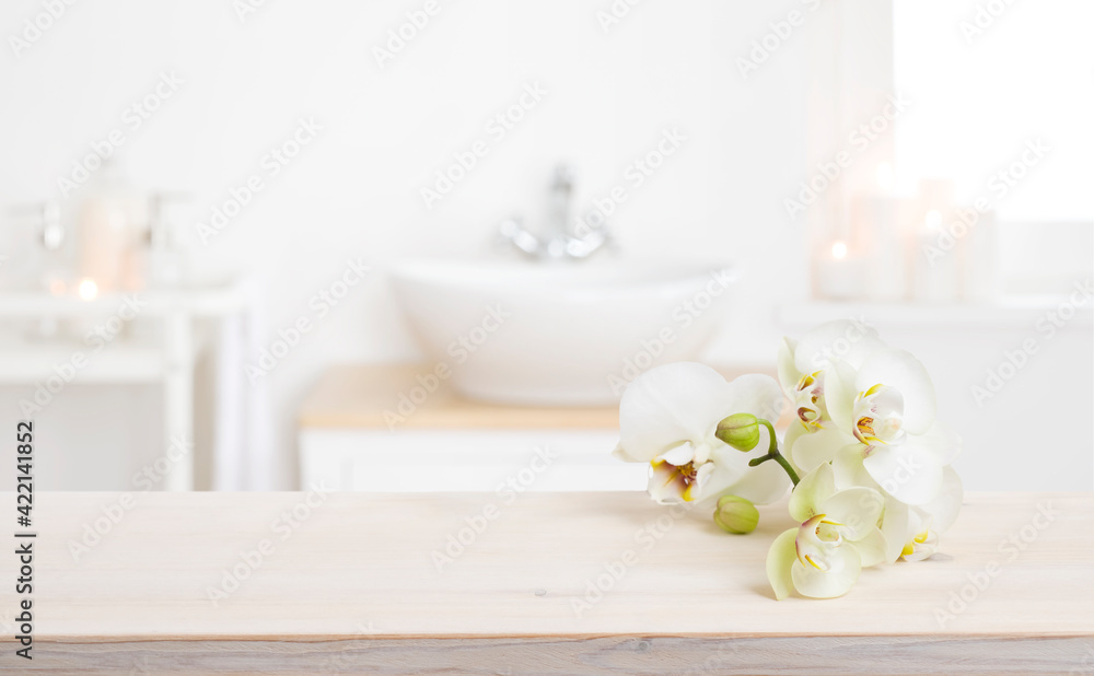 Orchid flowers on wooden table in blurred spa salon bathroom