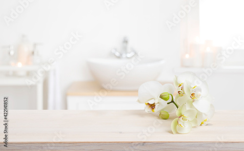 Orchid flowers on wooden table in blurred spa salon bathroom