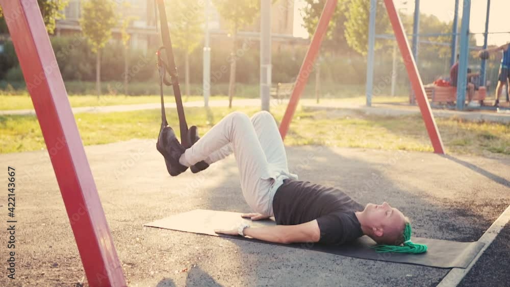 Young man with braided mohawk hairstyle doing exercise outdoors using overhead training.