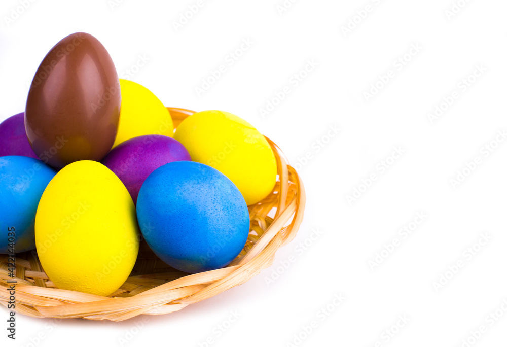 Easter chicken eggs painted in different colors and one chocolate in a wicker basket on a white background. Easter chicken eggs painted in different colors and one chocolate in a wicker basket on a white background.