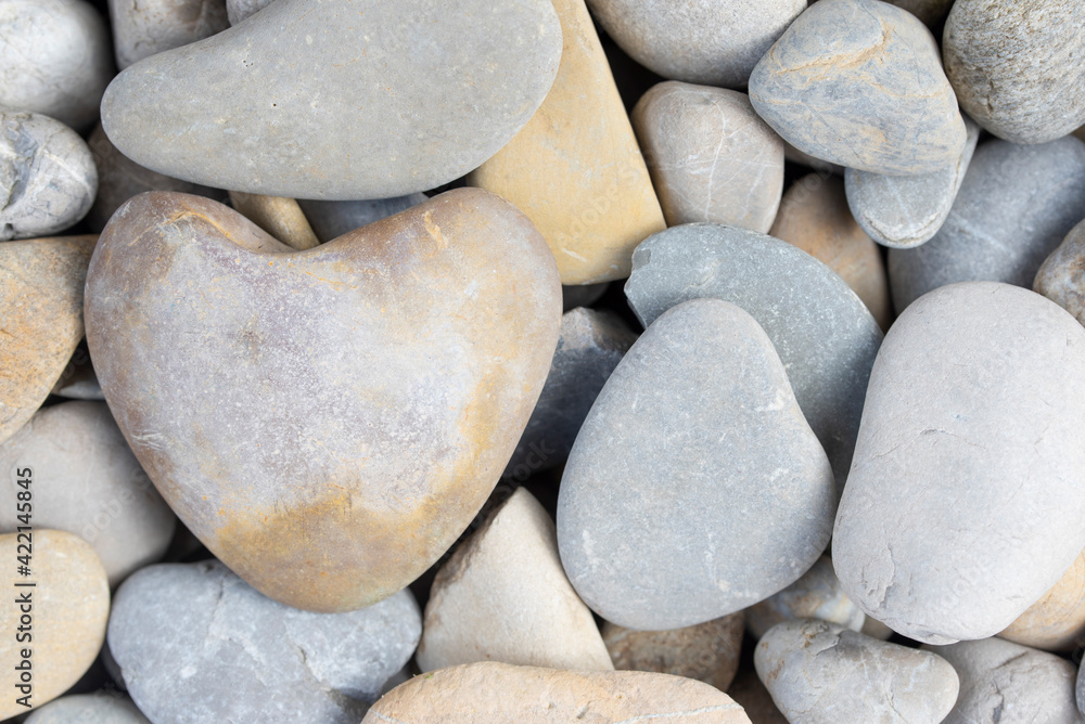 Background and texture of pebbles with a heart-shaped pebble between them Background and texture of pebbles with a heart-shaped pebble between them
