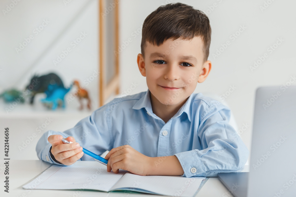 Clever kid doing homework using laptop and internet. Elementary school e-learning via video call. Boy studying online at home Clever kid doing homework using laptop and internet. Elementary school e-learning via video call. Boy studying online at home
