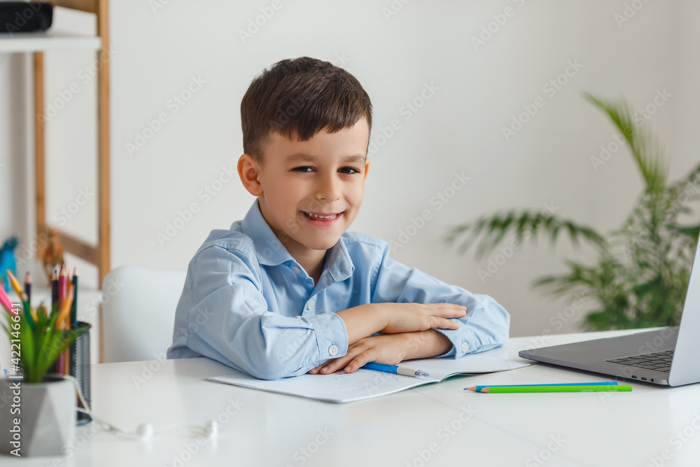 Clever kid doing homework using laptop and internet. Elementary school e-learning via video call. Boy studying online at home Clever kid doing homework using laptop and internet. Elementary school e-learning via video call. Boy studying online at home