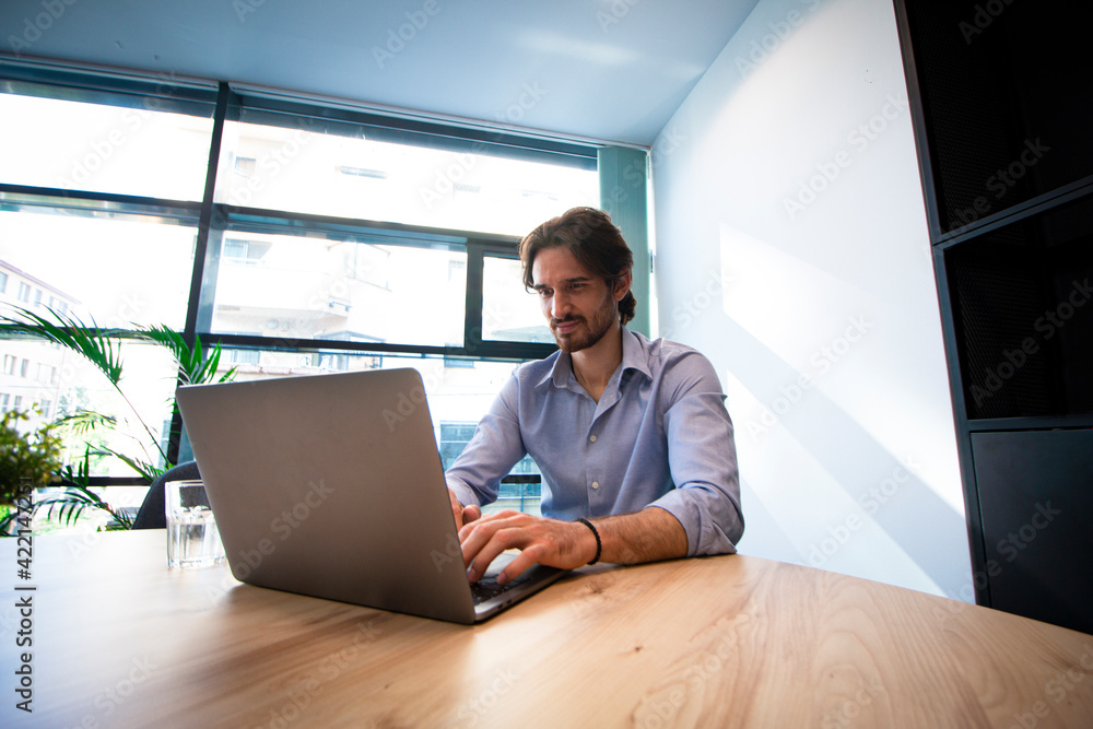 Low angle view of a young businessman using a laptop in the office Low angle view of a young businessman using a laptop in the office