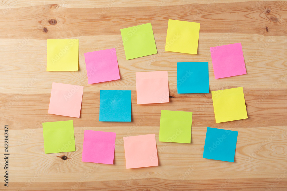 Multicolored sticky notes without text on the wooden table. Write the message or some information to remember it. Multicolored sticky notes without text on the wooden table. Write the message or some information to remember it.