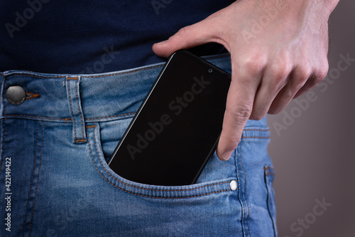 Smartphone in hand in a pocket in jeans