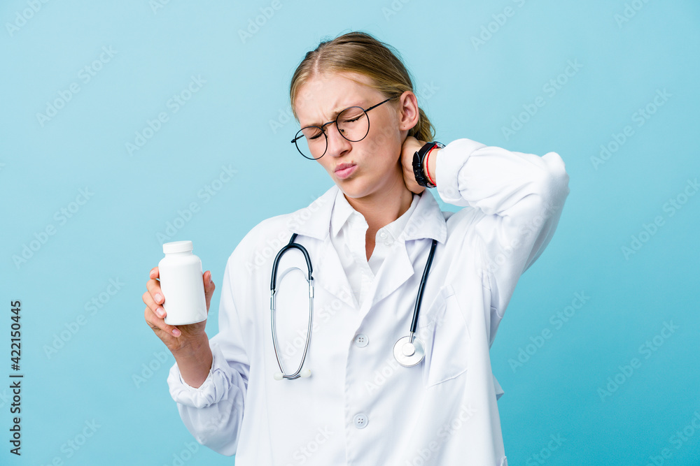 Young russian doctor woman holding pills bottle on blue suffering neck pain due to sedentary lifestyle. Young russian doctor woman holding pills bottle on blue suffering neck pain due to sedentary lifestyle.