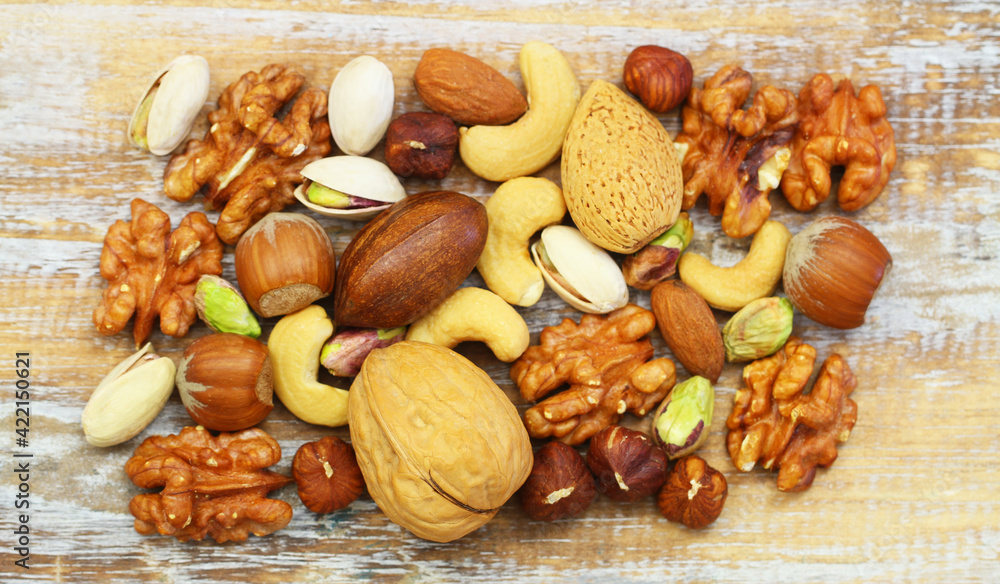 Selection of walnuts, pistachios, hazelnuts, cashew nuts and almonds on rustic wooden surface