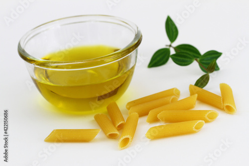 Obraz na płótnie Olive oil in glass bowl and uncooked penne rigate pasta
w salonie