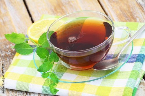 Obraz na płótnie Tea in transparent cup, fresh mint leaves on rustic wooden surface
w salonie