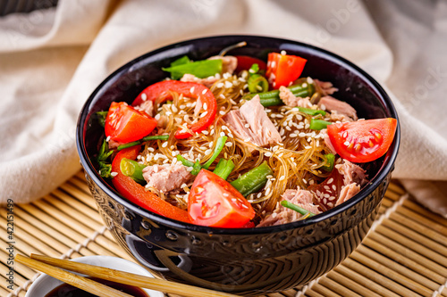 delicious glass noodles with tuna and vegetables on a dark wooden rustic background