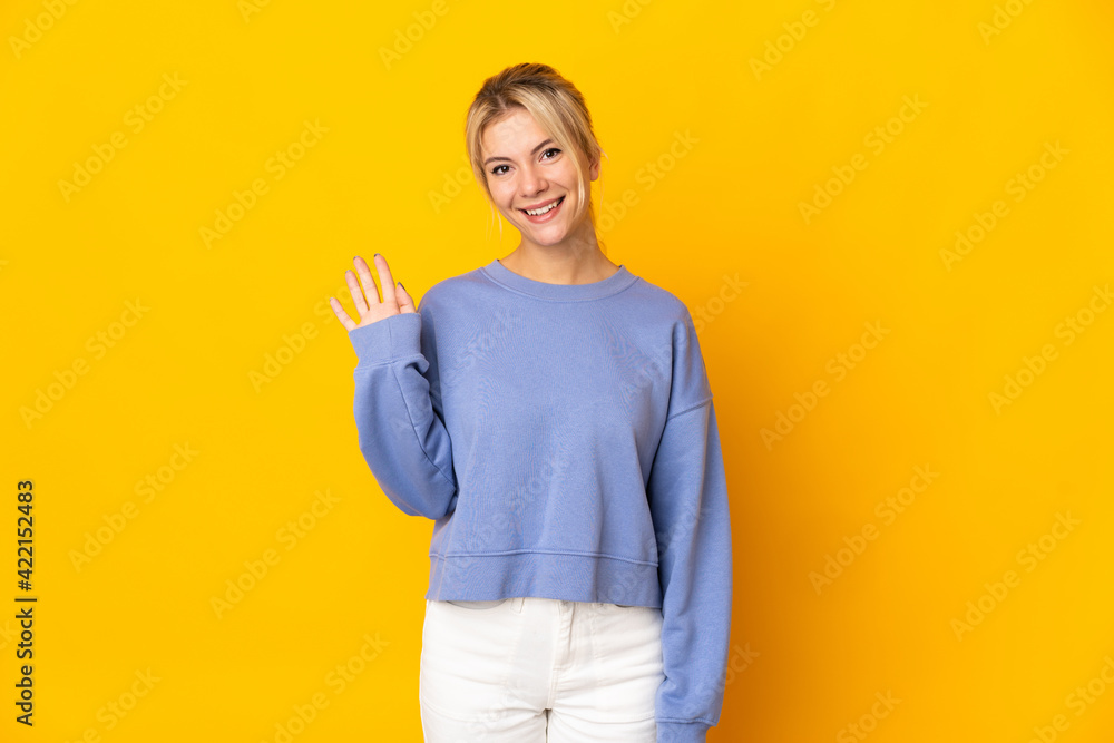 Young Russian woman isolated on yellow background saluting with hand with happy expression Young Russian woman isolated on yellow background saluting with hand with happy expression