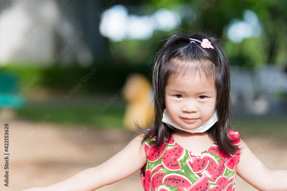 Cute girl playing in hot sun. Child sweats on forehead. Children puts mask under chin from discomfort. Wear mask to prevent air pollution and spread of coronavirus. Little kids is 3-4 years old. Cute girl playing in hot sun. Child sweats on forehead. Children puts mask under chin from discomfort. Wear mask to prevent air pollution and spread of coronavirus. Little kids is 3-4 years old.