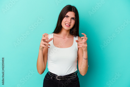 Young caucasian woman isolated on blue background upset screaming with tense hands.