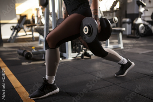Cropped shot of a woman doing lunges with weights