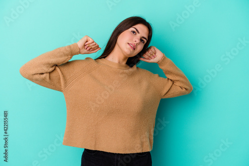 Young caucasian woman isolated on blue background stretching arms, relaxed position.