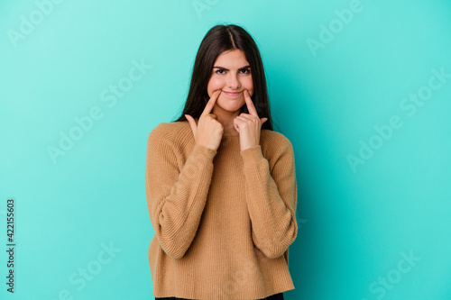 Young caucasian woman isolated on blue background doubting between two options.