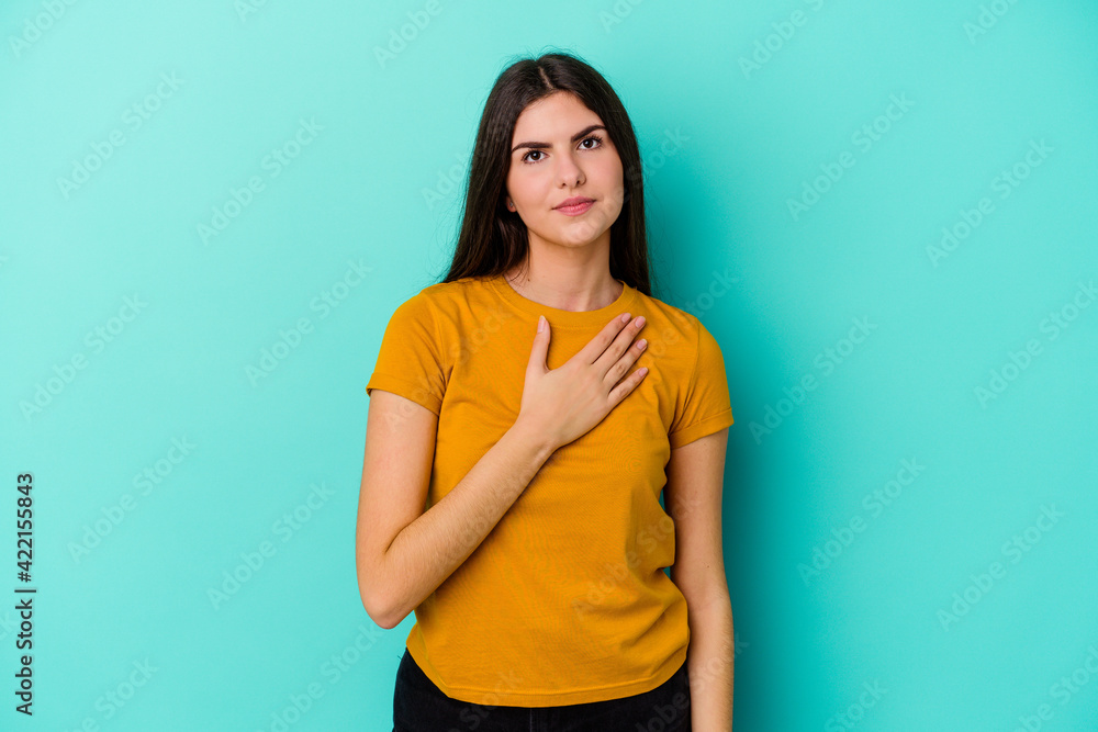 Young caucasian woman isolated on blue background taking an oath, putting hand on chest. Young caucasian woman isolated on blue background taking an oath, putting hand on chest.