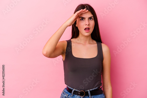 Young caucasian woman isolated on pink background shouts loud  keeps eyes opened and hands tense.