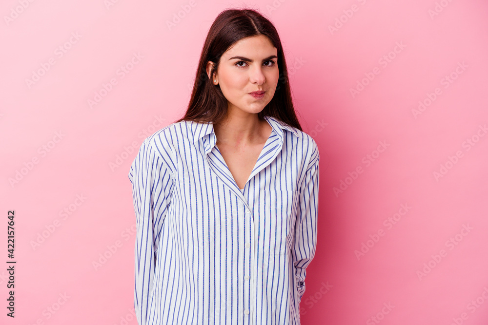 Young caucasian woman isolated on pink background shrugs shoulders and open eyes confused. Young caucasian woman isolated on pink background shrugs shoulders and open eyes confused.