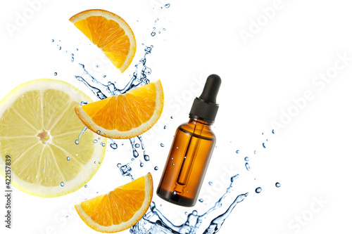 Dark brown glass bottle of face serum with vitamin C or essential oil and orange slices flying in splashing water	 photo