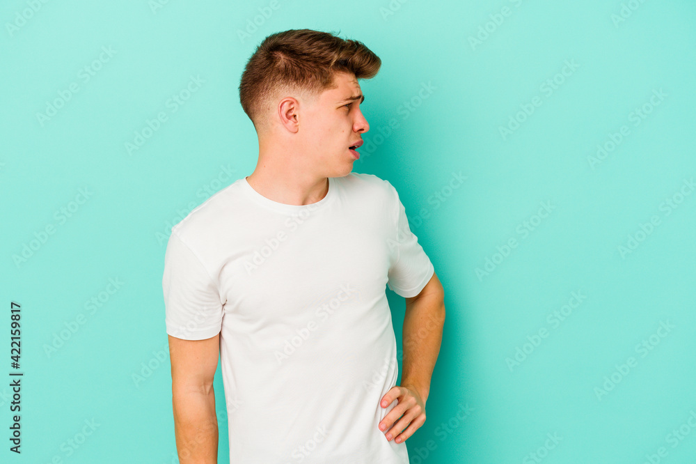 Young caucasian man isolated on blue background suffering a back pain. Young caucasian man isolated on blue background suffering a back pain.