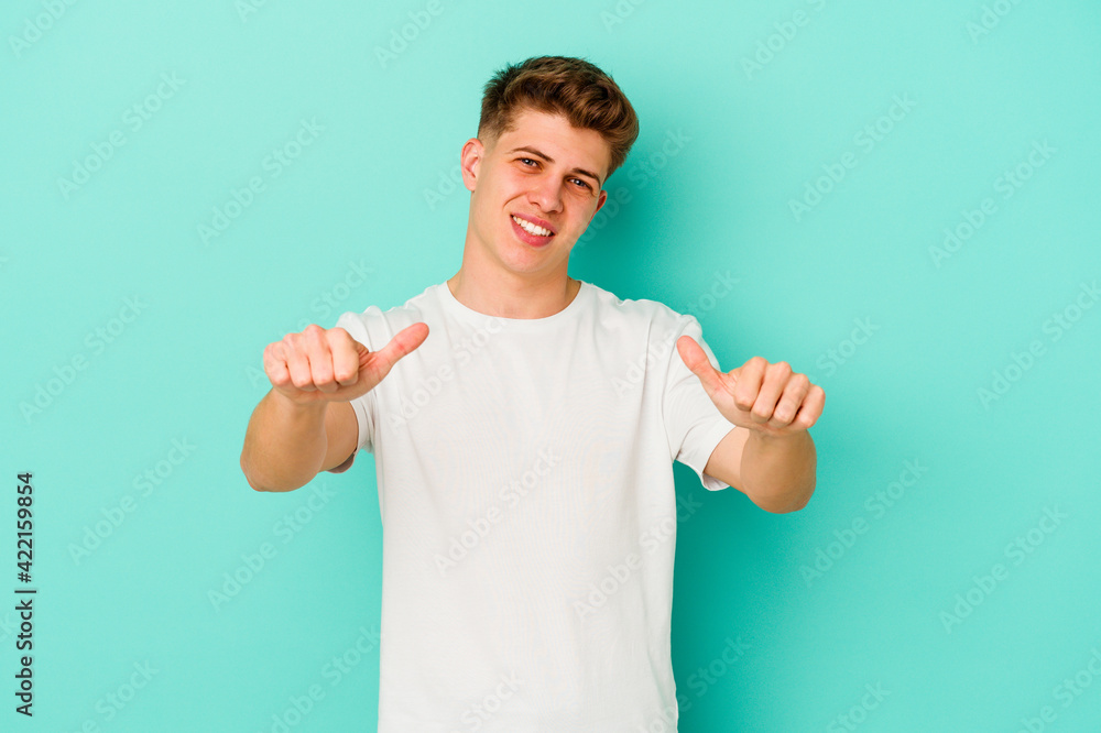 Young caucasian man isolated on blue background raising both thumbs up, smiling and confident. Young caucasian man isolated on blue background raising both thumbs up, smiling and confident.