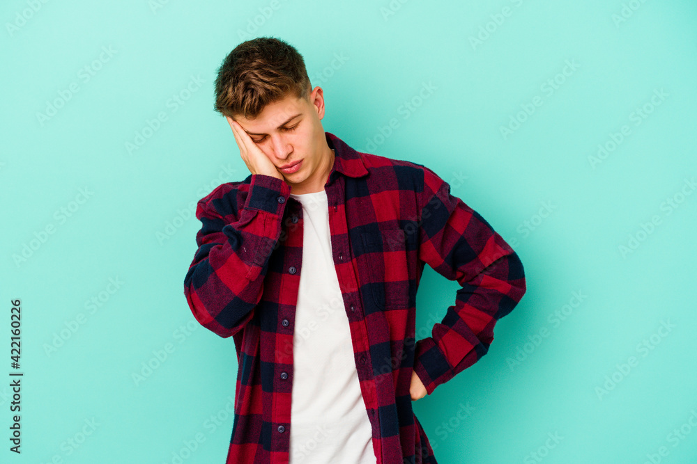 Young caucasian man isolated on blue background who is bored, fatigued and need a relax day. Young caucasian man isolated on blue background who is bored, fatigued and need a relax day.